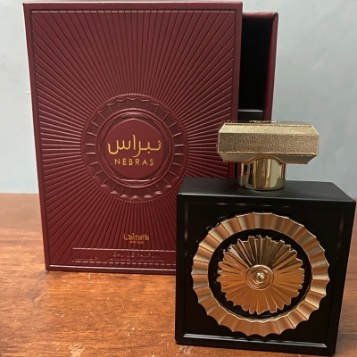 Perfume preto com detalhes dourados em caixa vermelha texturada