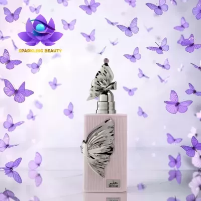 Frasco de perfume rosa com borboletas metálicas e borboletas lilás ao fundo.