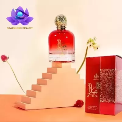 Frasco de perfume vermelho e transparente com tampa dourada ao lado de caixa vermelha decorada com flores