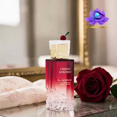Frasco de perfume gradiente vermelho e transparente com tampa dourada e cereja decorativa, decorado com rosa vermelha e pano bordado
