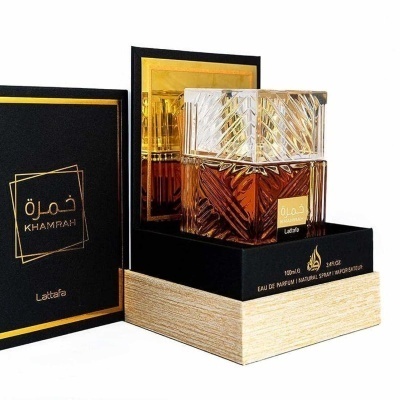 Frasco de perfume dourado e âmbar em caixa preta e madeira clara