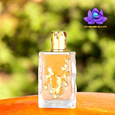 Frasco de perfume transparente com tampa dourada sobre superfície alaranjada