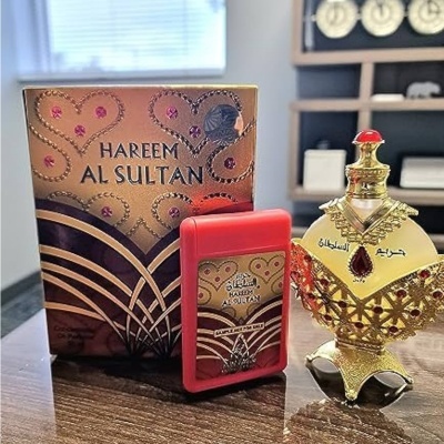 Conjunto de perfume dourado com embalagem e frasco decorativo em cima de mesa de madeira.