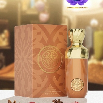 Frasco de perfume dourado com caixa castanha ao lado, especiarias na frente e fundo desfocado.