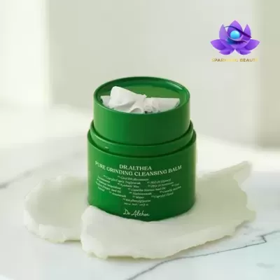 Frasco verde de bálsamo de limpeza DR.ALTHEA com creme branco e logótipo SPARKLING BEAUTY em fundo claro