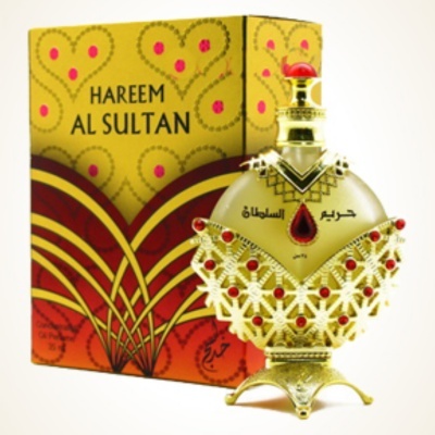 Frasco de perfume HAREEM AL SULTAN dourado com detalhes vermelhos ao lado da embalagem colorida amarela e vermelha.