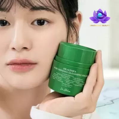 Frasco verde de Dr.Althea Pure Grinding Cleansing Balm na mão de mulher com pele clara