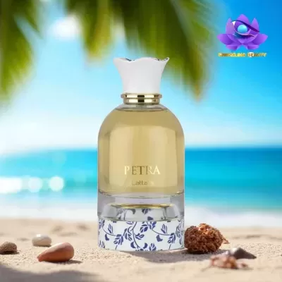 Frasco de perfume PETRA sobre areia de praia com fundo mar e palmeiras