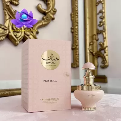 Frasco de perfume rosa claro com detalhes dourados e caixa texturizada rosa com texto, sobre superfície e fundo decorado.