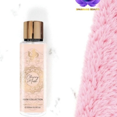 Frasco de spray corporal Cherry Musk com tampa dourada ao lado de tecido felpudo rosa