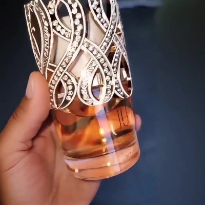 Frasco de perfume decorativo com tampa dourada e líquido âmbar