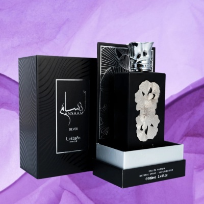 Frasco de perfume preto com flores brancas e caixa preta sobre fundo roxo