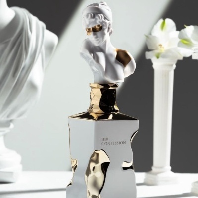 Frasco de perfume prateado e dourado com estátua branca no topo