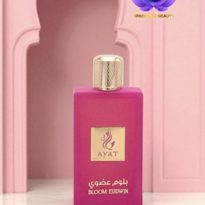 Frasco de perfume rosa fosco com tampa dourada e etiquetas douradas colocado sobre mármore, fundo rosa com arco