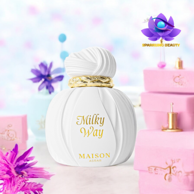 Frasco de perfume branco Milky Way com detalhes dourados ao lado de caixas rosas e flores lilases.