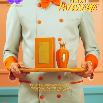 Homem de blazer cinza claro com detalhes laranja segurando bandeja com perfume e caixa laranja