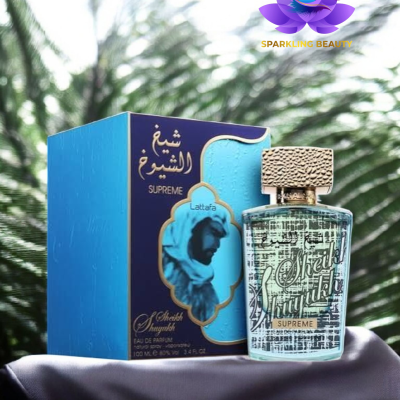 Frasco de perfume transparente com tampa dourada ao lado de caixa azul com detalhes dourados e imagem de homem árabe.