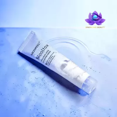 Tubo branco de máscara facial Mooltox sobre superfície azul molhada com logótipo Sparkling Beauty