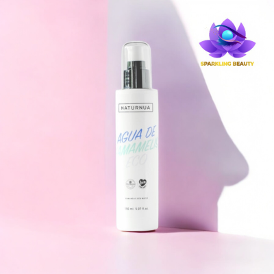 Frasco branco de água de hamamélis NaturNua sobre fundo rosa com sombra e logo Sparkling Beauty