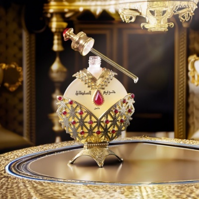 Frasco de perfume dourado com pedras vermelhas numa bandeja dourada