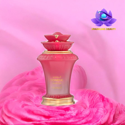 Frasco de perfume rosado com tampa decorativa e texto dourado sobre tecido rosa
