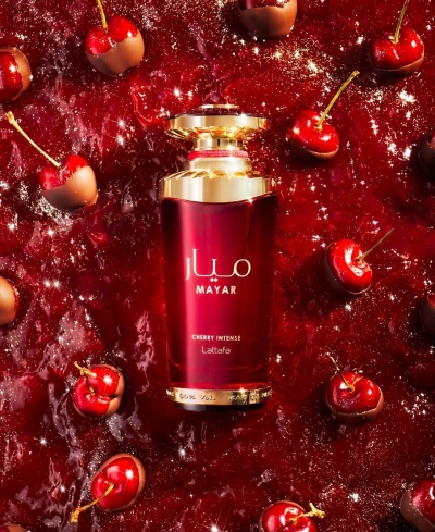 Frasco de perfume Mayar Cherry Intense com cerejas e chocolate sobre superfície vermelha