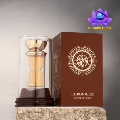 Frasco dourado de perfume e caixa castanha com texto Chronicles Extrait de Parfum