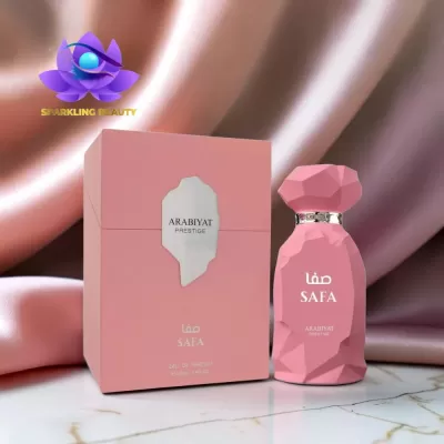 Frasco e caixa de perfume rosa ARABIYAT PRESTIGE SAFA sobre superfície mármore com fundo de tecido rosa