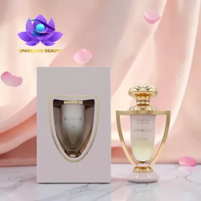 Frasco de perfume Arabiyat Prestige EXTRADOSE FEMME com caixa branca sobre superfície de mármore e fundo rosa com pétalas