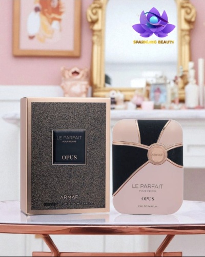 Frasco e caixa de perfume Le Parfait OPUS ARMAF sobre mesa branca em ambiente decorado em tons rosa e dourado