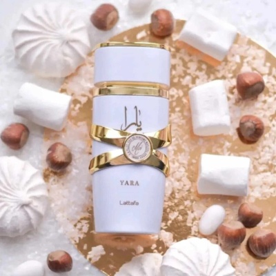 Frasco de perfume branco e dourado YARA da Lattafa com marshmallows e avelãs ao redor