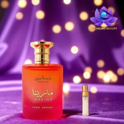 Frasco vermelho de perfume Marina Taskeen Paris Corner sobre tecido roxo com luzes desfocadas