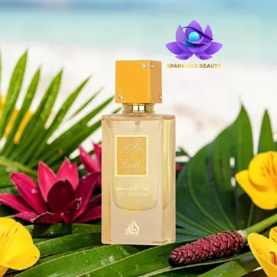 Frasco de perfume transparente com tampa amarela sobre folhas verdes e flores coloridas