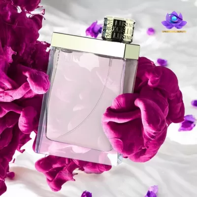Frasco de perfume com líquido rosa rodeado por pétalas coloridas