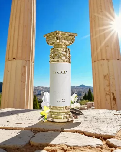 Frasco de perfume branco e dourado entre colunas antigas ao sol