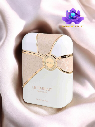 Frasco de perfume branco e bege com detalhes dourados sobre tecido de cetim rosa claro