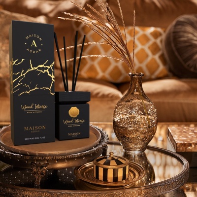 Difusor de aroma preto e dourado com vaso decorativo e caixa numa mesa redonda num ambiente aconchegante.