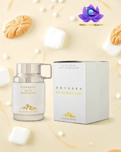 Frasco e caixa de perfume Odyssey Eau de Montagne Mountain Edition branco e dourado, com fundo creme decorado com marshmallows e bolachas