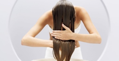 Mulher a pentear cabelo molhado com as mãos, roupa branca, fundo cinzento claro circular