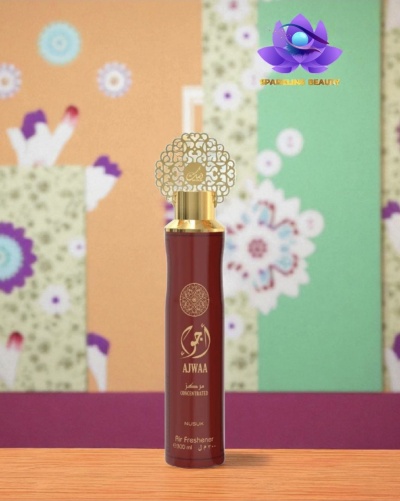 Frasco de perfume vermelho AJWAA com tampa dourada decorativa sobre mesa com fundo floral colorido