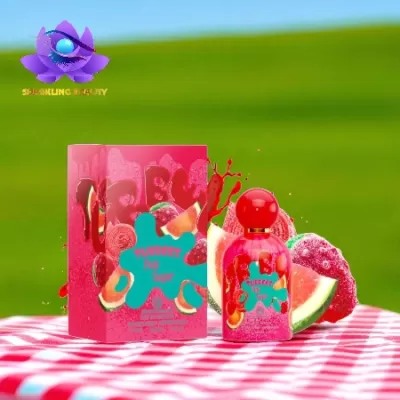 Frasco e caixa de perfume rosa com desenhos de frutas sobre toalha xadrez.