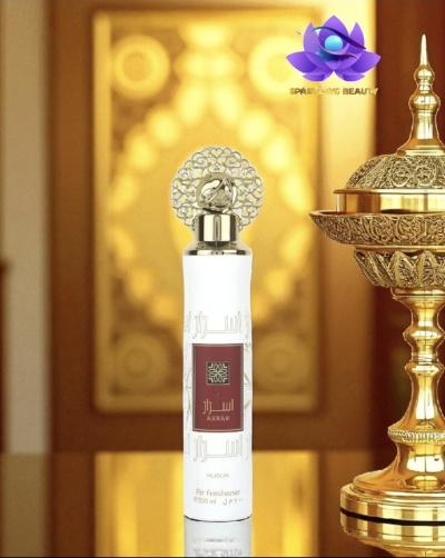 Frasco branco de spray ambientador com tampa prateada e objeto decorativo dourado