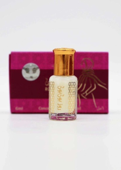 Frasco pequeno com líquido branco e caixa rosa e vermelha ao fundo