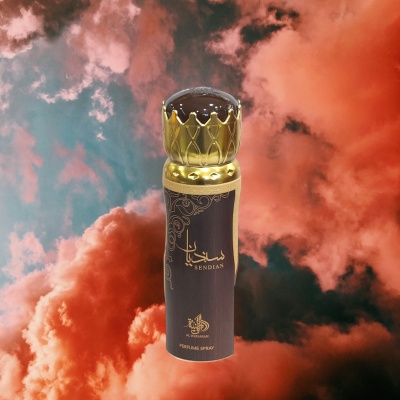 Frasco de perfume preto e dourado com tampa em forma de coroa sobre fundo de céu com nuvens coloridas