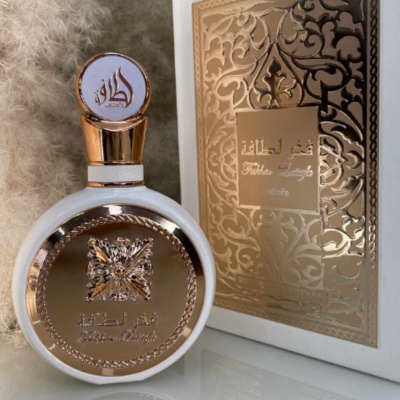 Frasco e embalagem de perfume branco e dourado com texto em árabe e inglês
