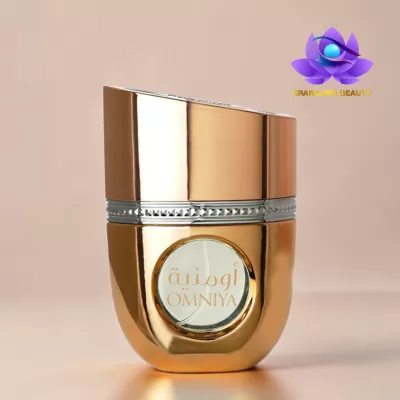 Frasco de perfume dourado com janela circular e texto OMNIYA em fundo bege