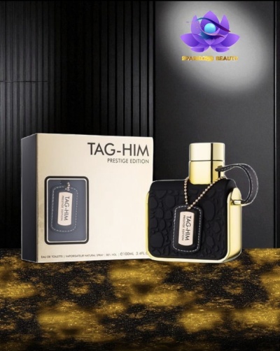 Frasco de perfume TAG-HIM Prestige Edition preto e dourado ao lado da caixa em fundo escuro