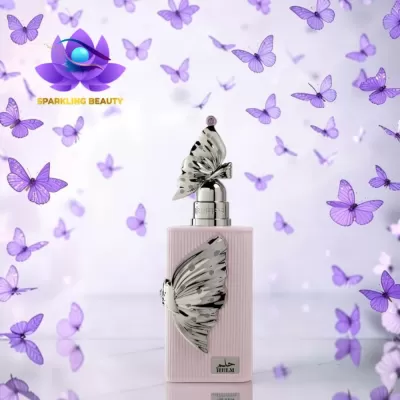 Frasco de perfume rosa com borboletas metálicas e borboletas lilás ao fundo.