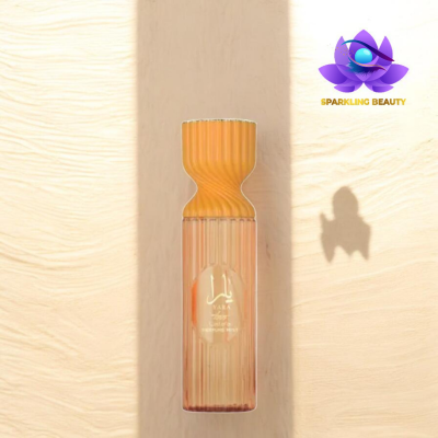 Frasco de borrifador para corpo transparente com tampa laranja e etiqueta dourada