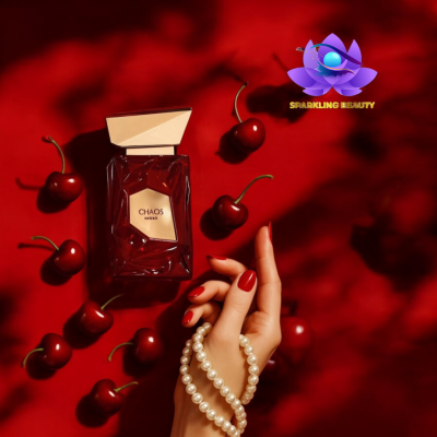 Frasco de perfume vermelho com cerejas e mão feminina com colar de pérolas.